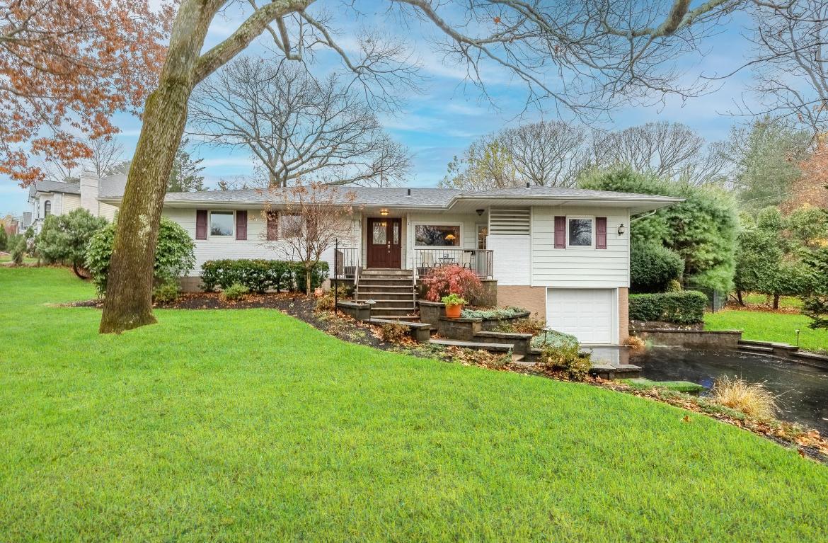 View of front of property featuring a front yard, a porch, and a garage