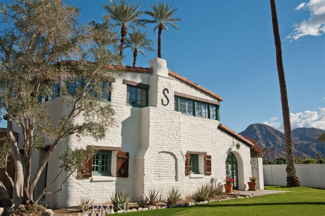 a view of a white house with large windows and a small yard