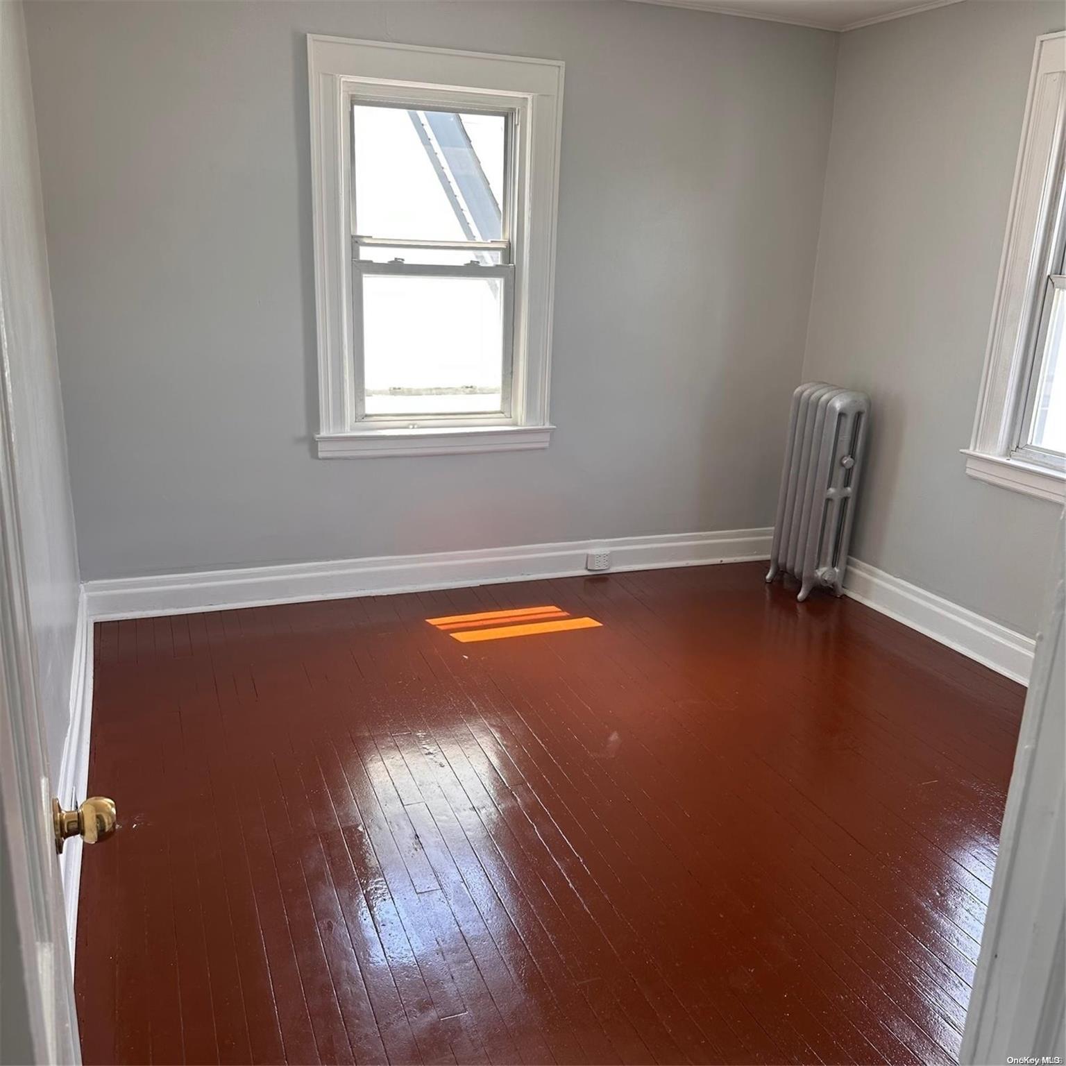 an empty room with a window and wooden floor