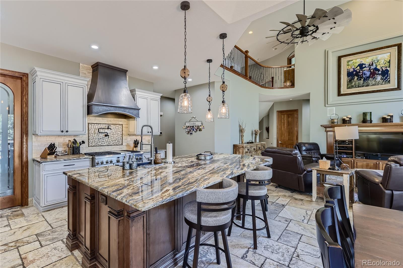 a open kitchen with stainless steel appliances granite countertop a stove top oven a refrigerator a sink dishwasher a dining table and chairs with wooden floor