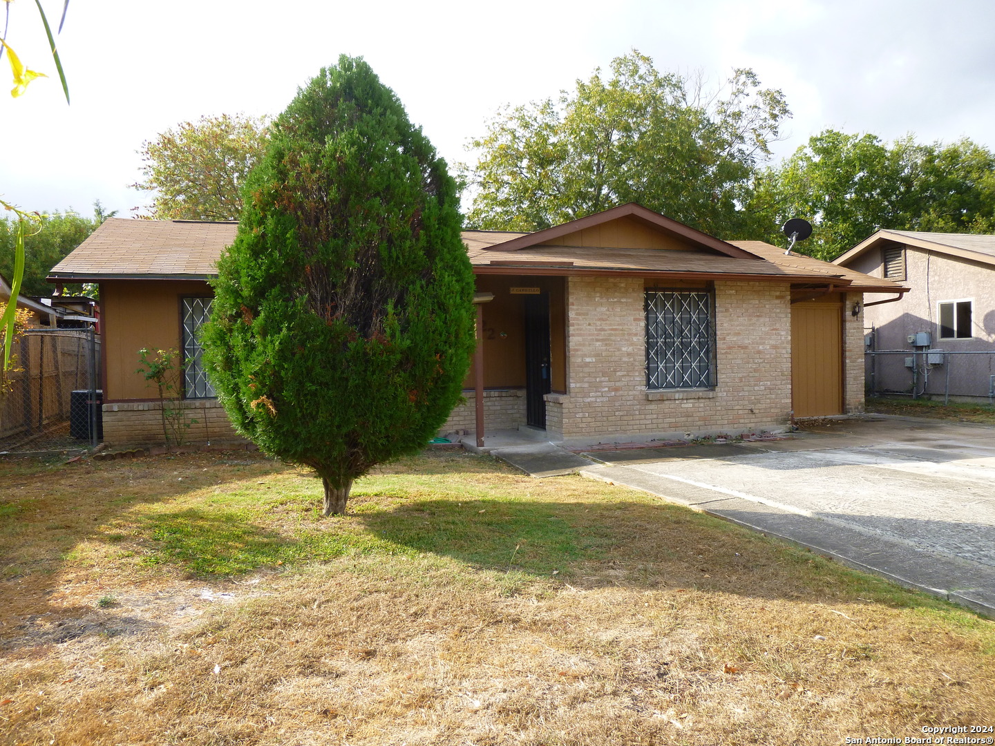 a view of a house with a yard and large tree