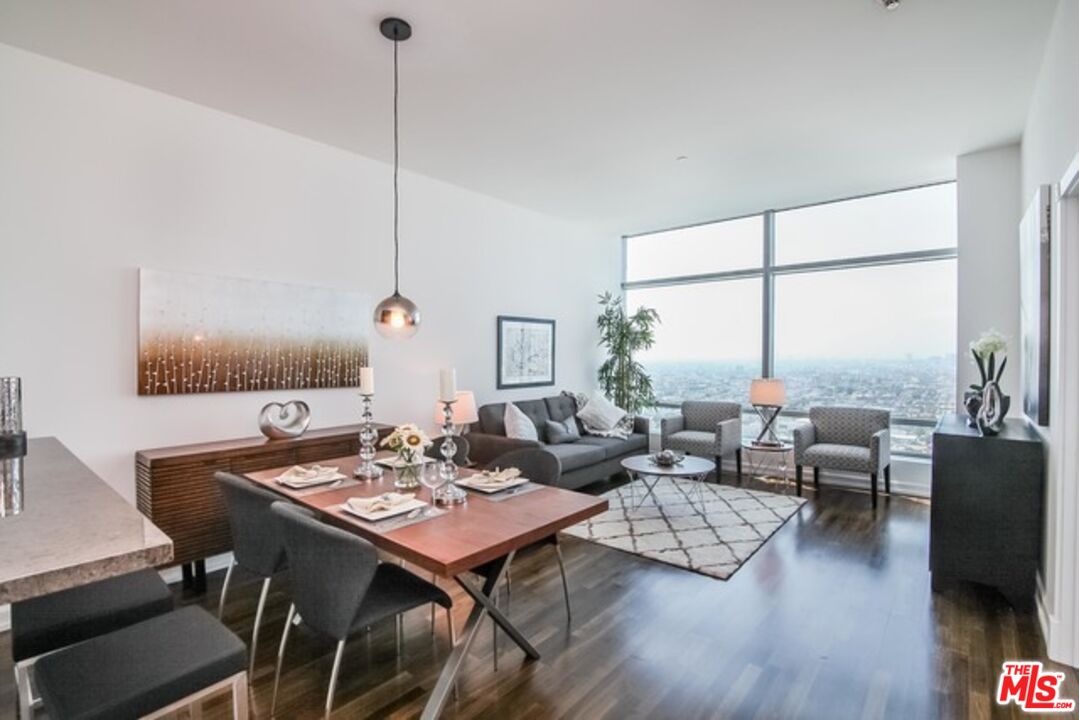 a living room with furniture floor to ceiling window and wooden floor