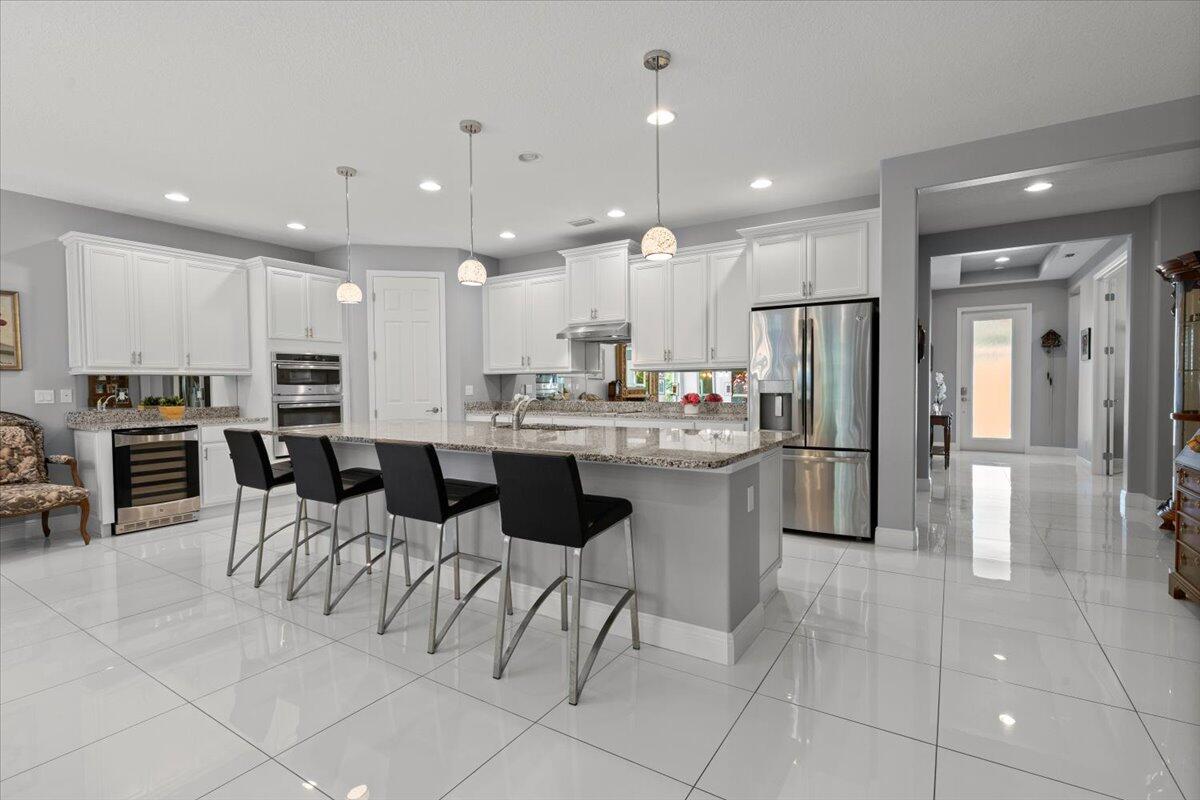 a kitchen with stainless steel appliances kitchen island granite countertop a refrigerator a oven a sink a dining table and chairs