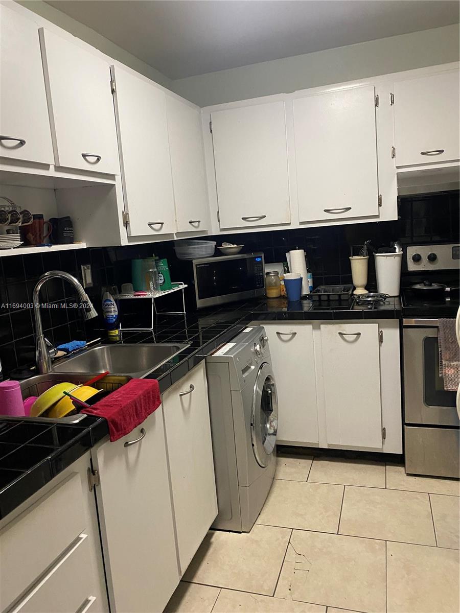 a kitchen with granite countertop a sink a stove and cabinets