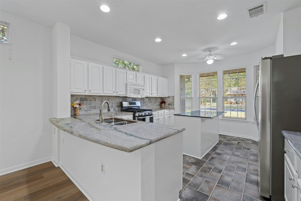 a kitchen with a refrigerator a sink a stove a microwave and cabinets