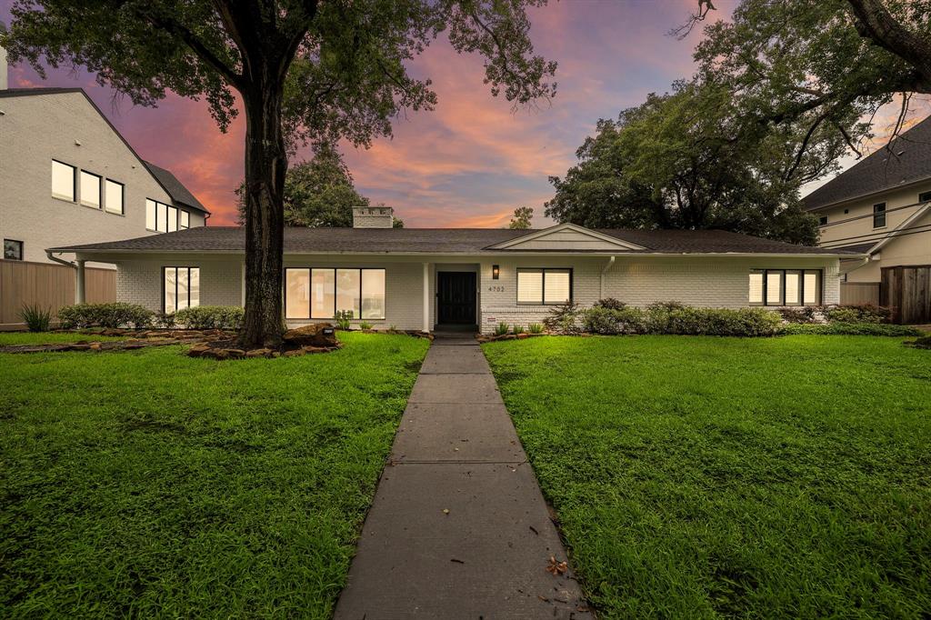 a front view of a house with a garden and trees