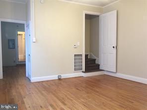 an empty room with wooden floor and hallway