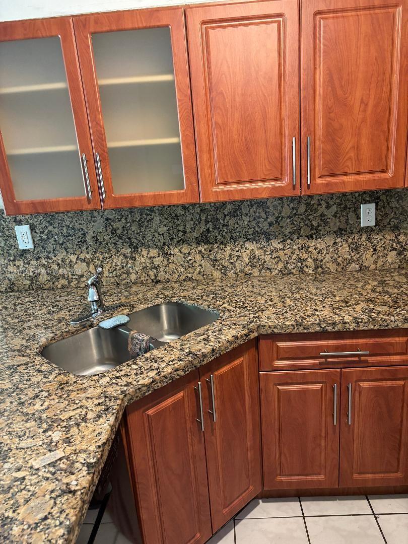 a kitchen with granite countertop a sink and a wooden cabinets