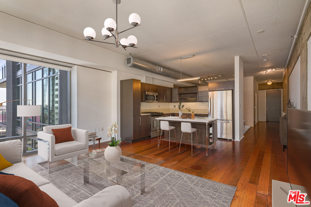 a living room with lots of furniture dining table a large window and stainless steel appliances