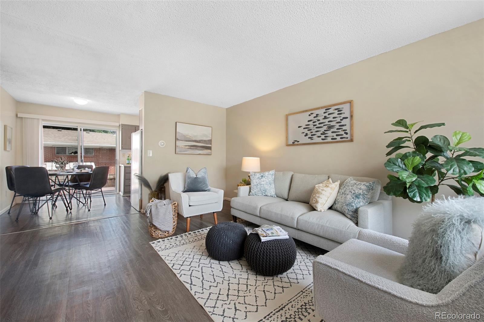 a living room with furniture a wooden floor and a potted plant