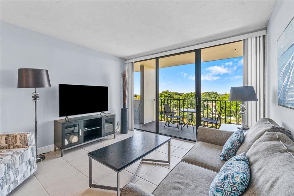 a living room with furniture a flat screen tv and a floor to ceiling window