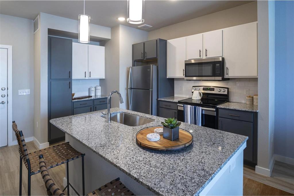 a kitchen with stainless steel appliances granite countertop a kitchen island hardwood floor and a refrigerator