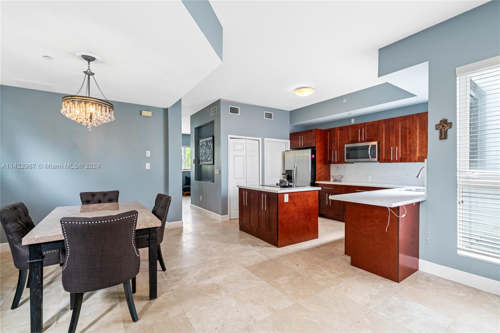 a kitchen with stainless steel appliances kitchen island granite countertop a table chairs in it and a window