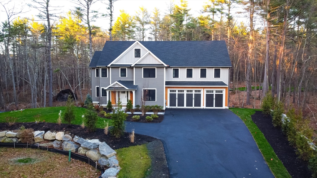 a view of a brick house with a yard plants and large tree