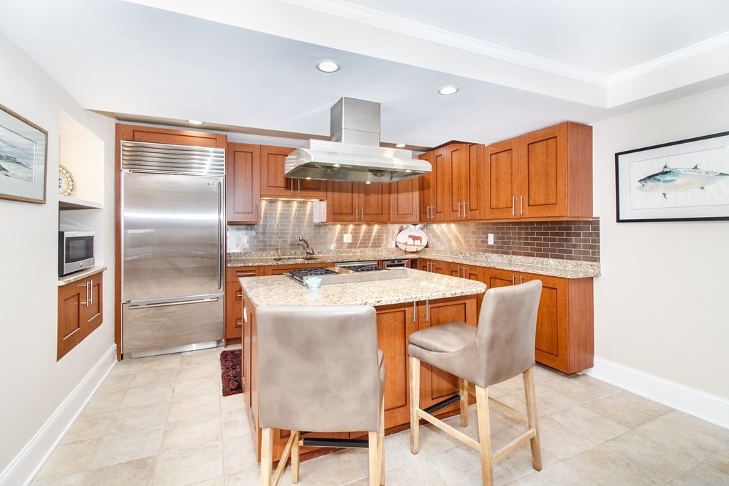a kitchen with stainless steel appliances granite countertop a stove top oven a refrigerator and a dining table