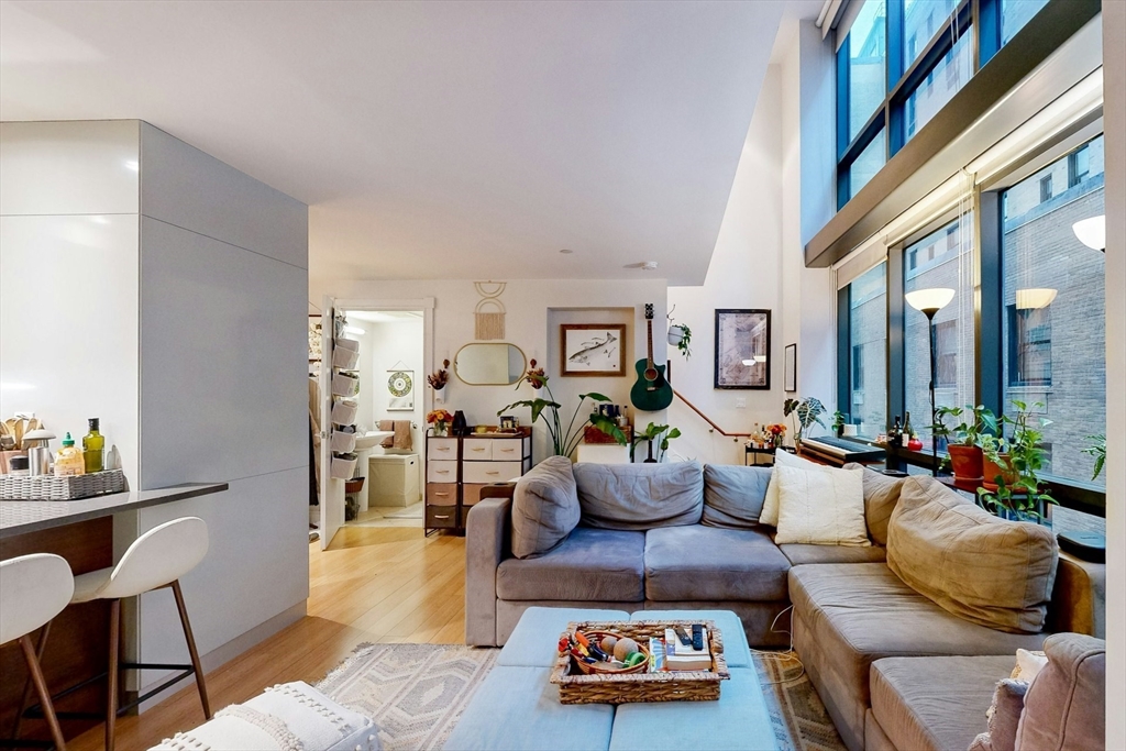 a living room with furniture kitchen view and a large window