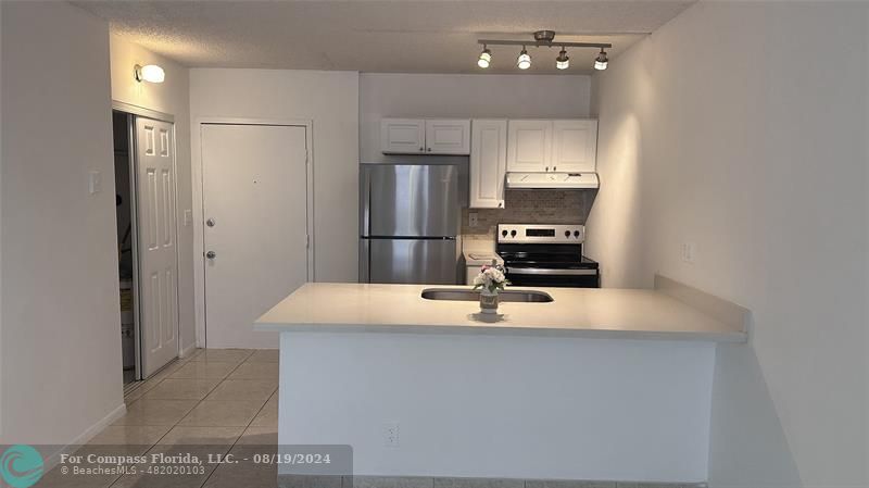 a kitchen with kitchen island a refrigerator and a stove