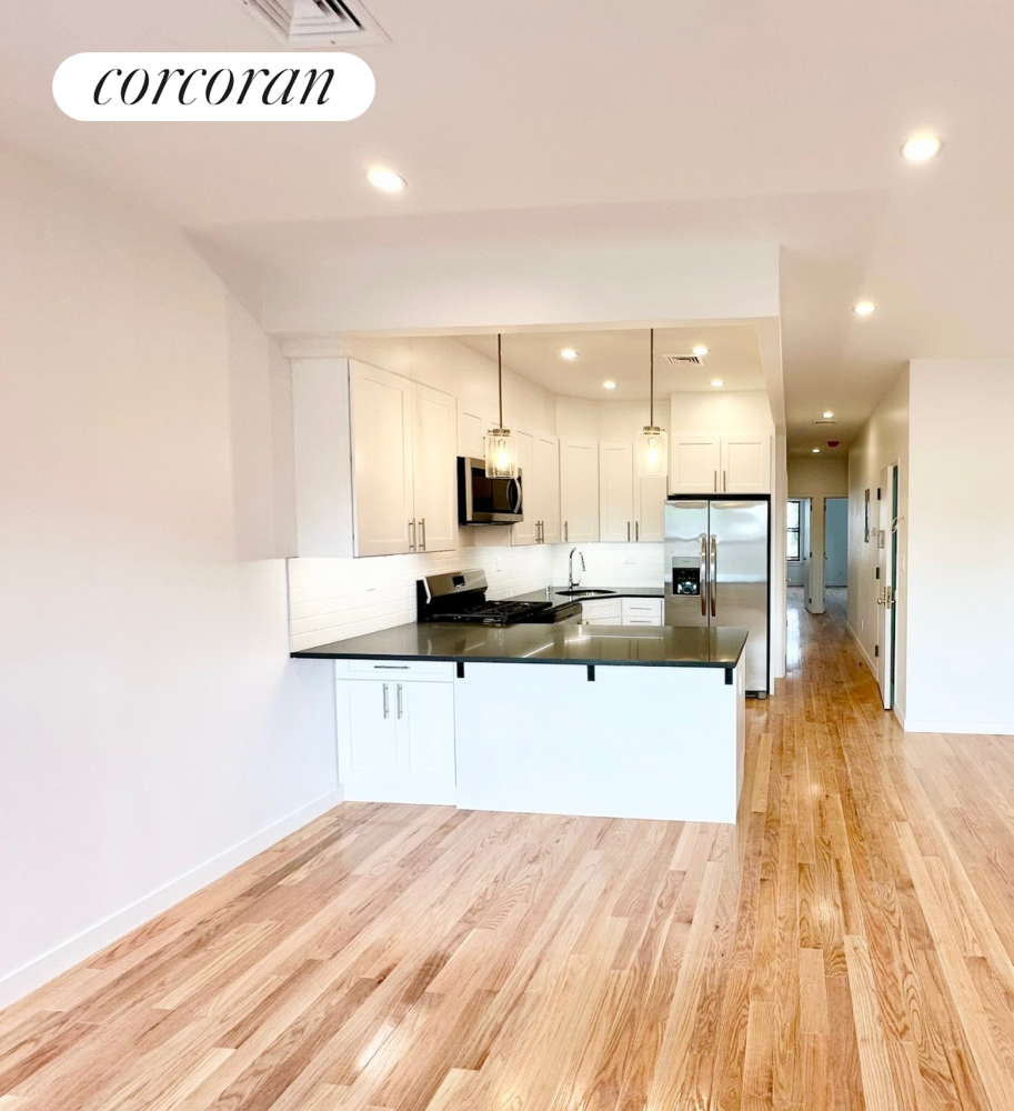 a large kitchen with kitchen island a sink wooden floor and stainless steel appliances