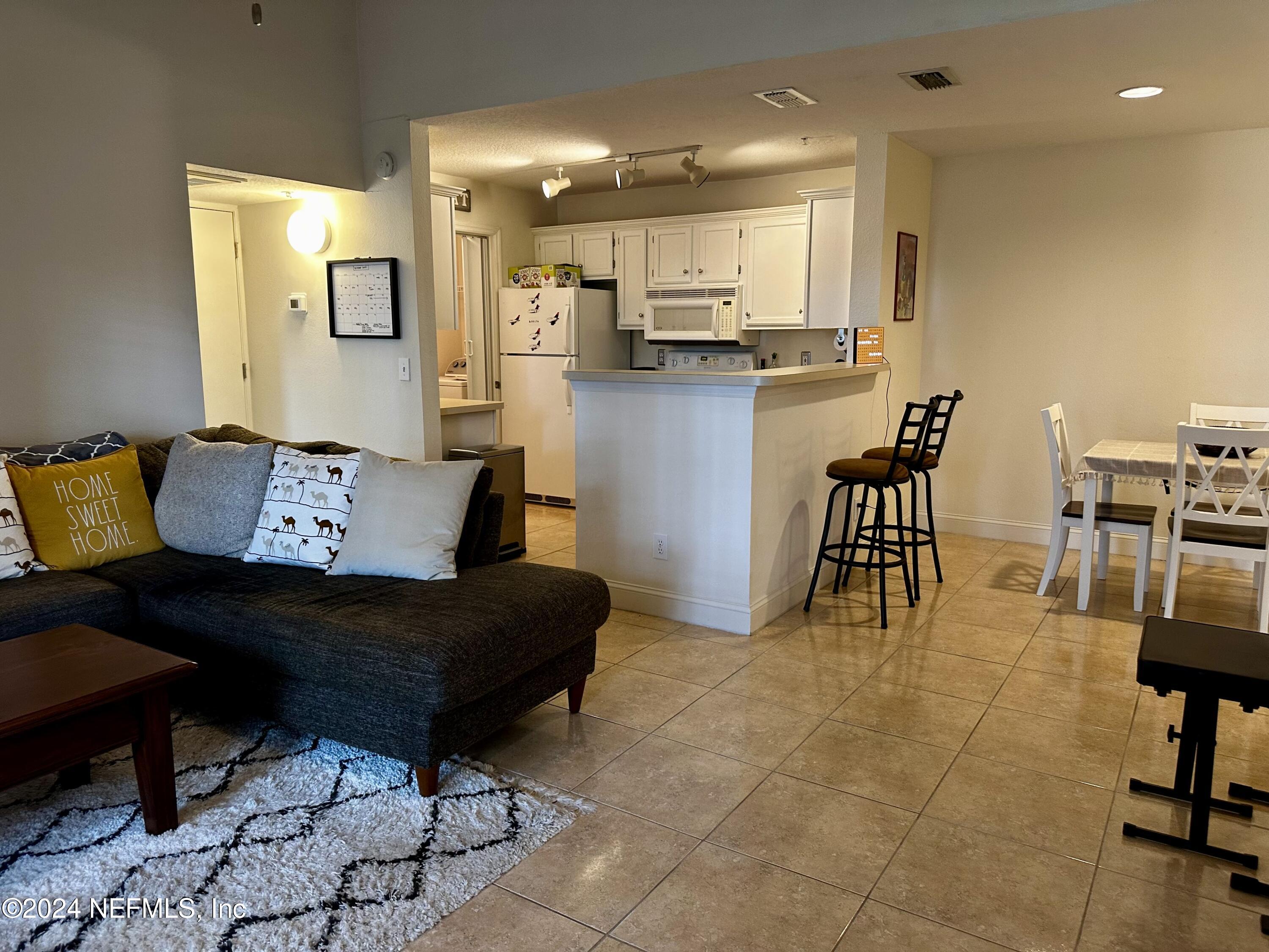 a living room with stainless steel appliances kitchen island granite countertop furniture and a dining table