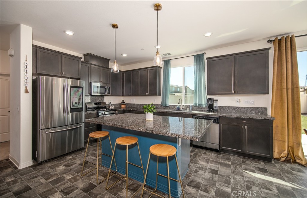 a large kitchen with granite countertop a stove refrigerator and microwave