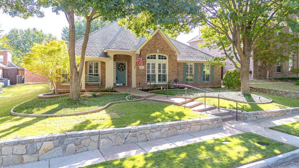 The well-manicured landscaping and curved stone pathway lead you to a spacious front porch, perfect for sitting and enjoying the neighborhood.