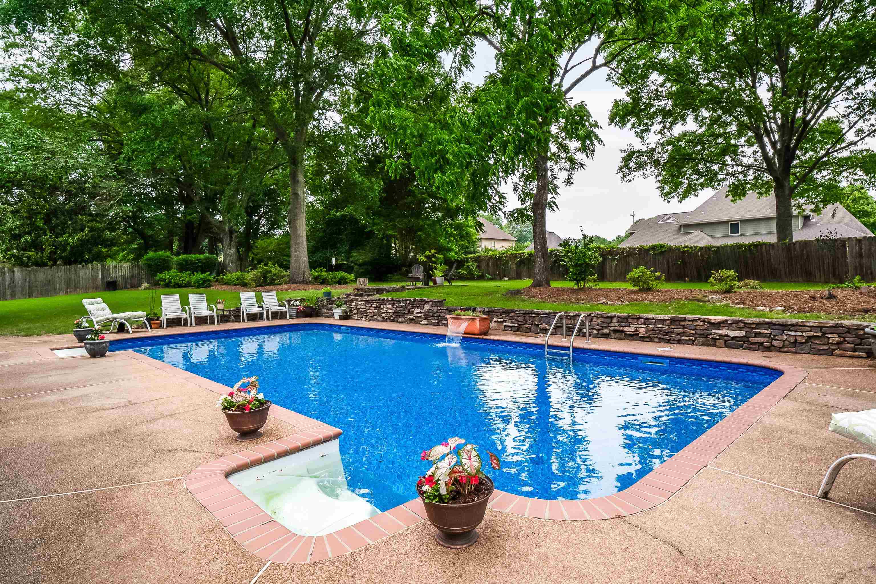 a view of a swimming pool with a patio and a yard