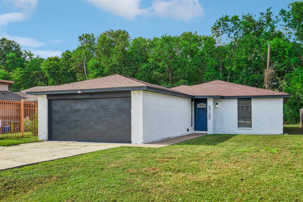 a front view of house with yard and trees in the background