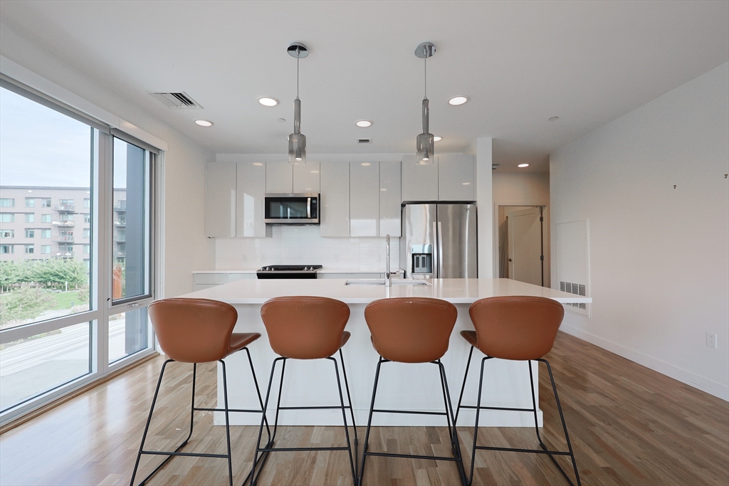 a kitchen with granite countertop a counter space chairs stainless steel appliances and cabinets