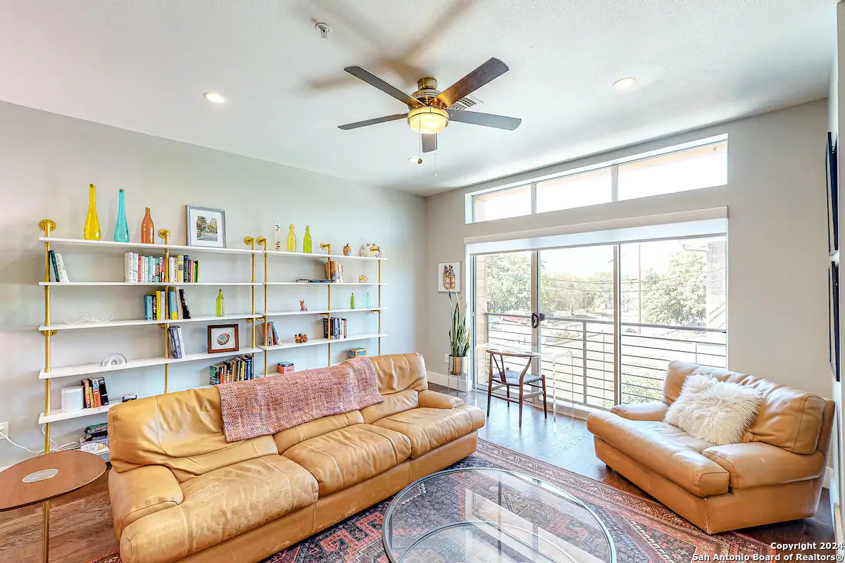 a living room with furniture and a large window with bookshelf