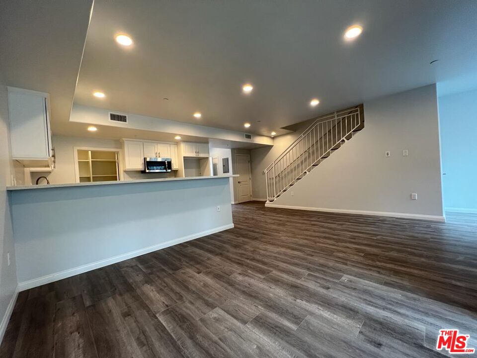 a view of a big room with wooden floor and windows