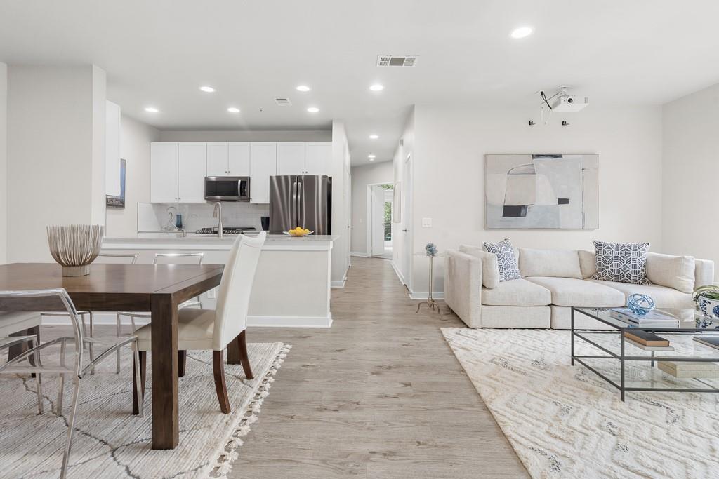 a living room with furniture a wooden floor and kitchen view