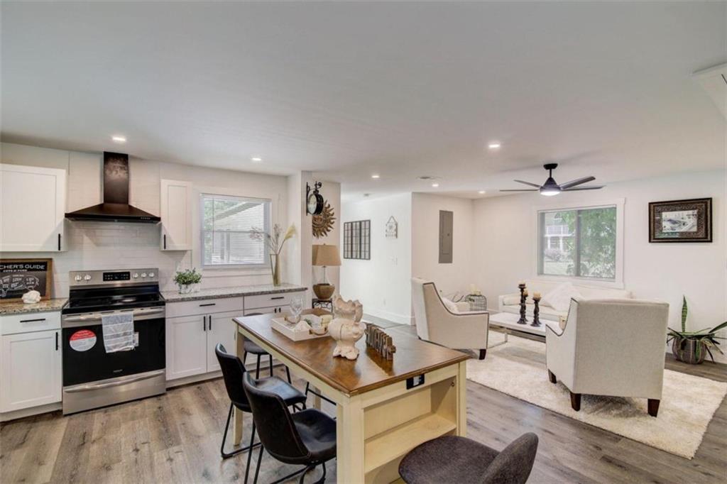 a kitchen with granite countertop a stove a sink a dining table and chairs