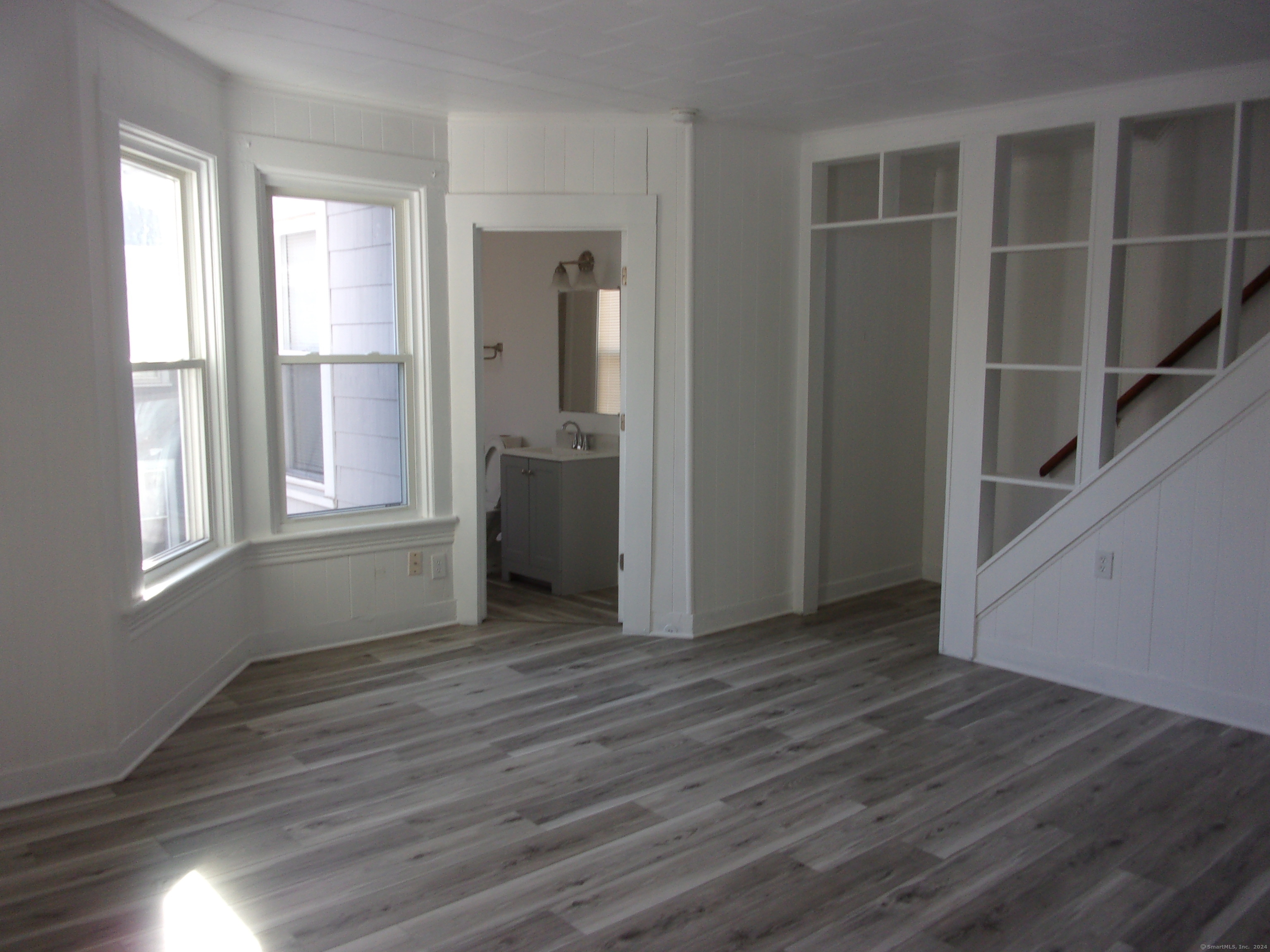 a view of empty room with wooden floor and fan