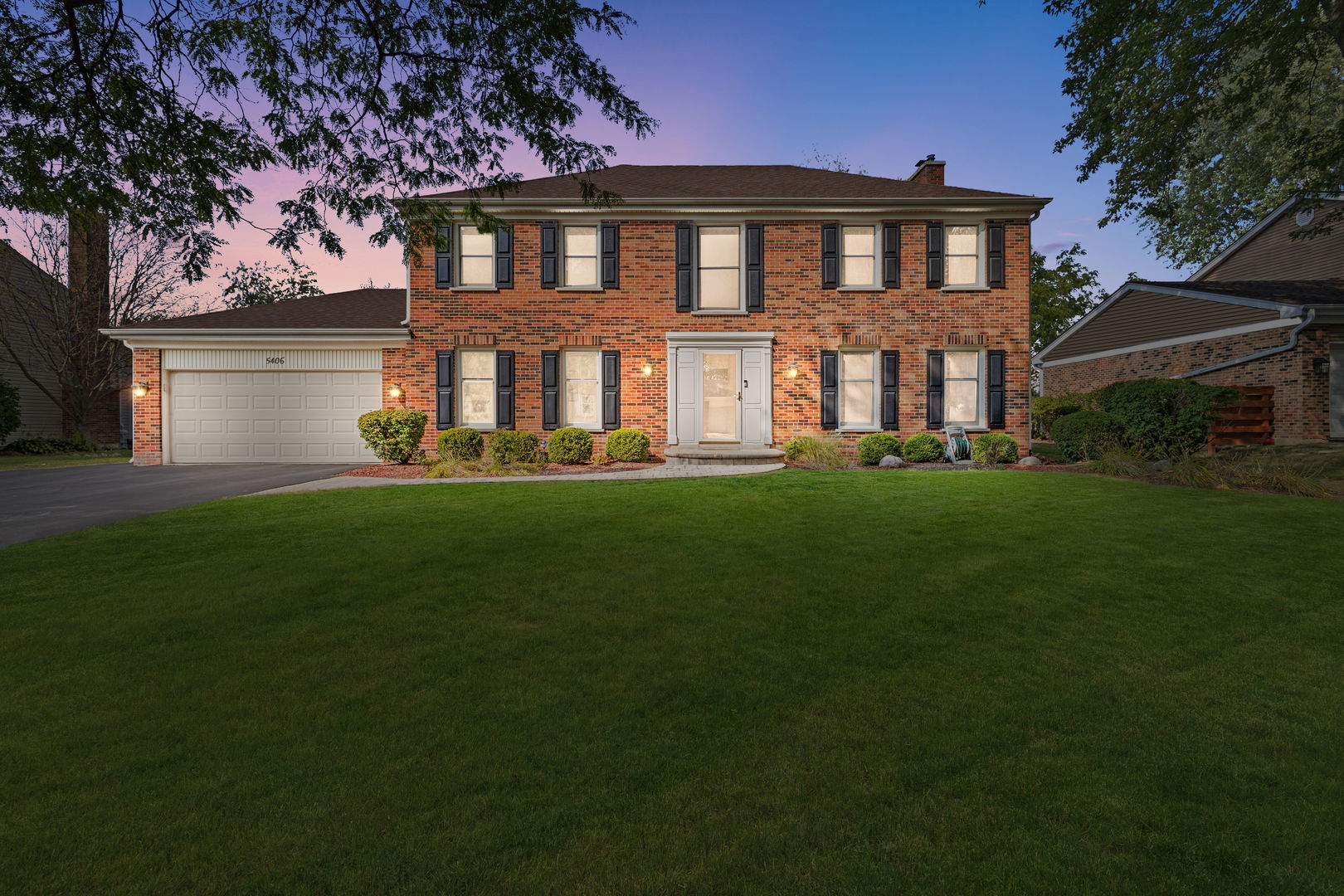 a front view of a house with a garden and trees