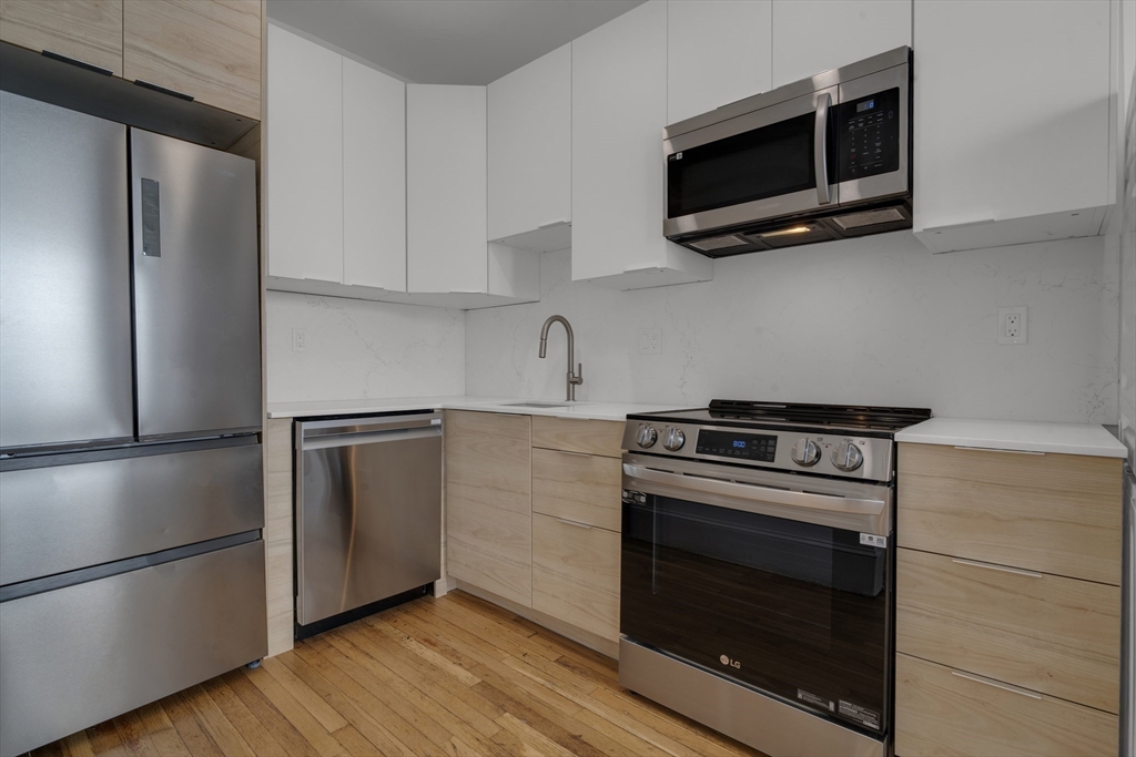 a kitchen with cabinets stainless steel appliances and wooden floor