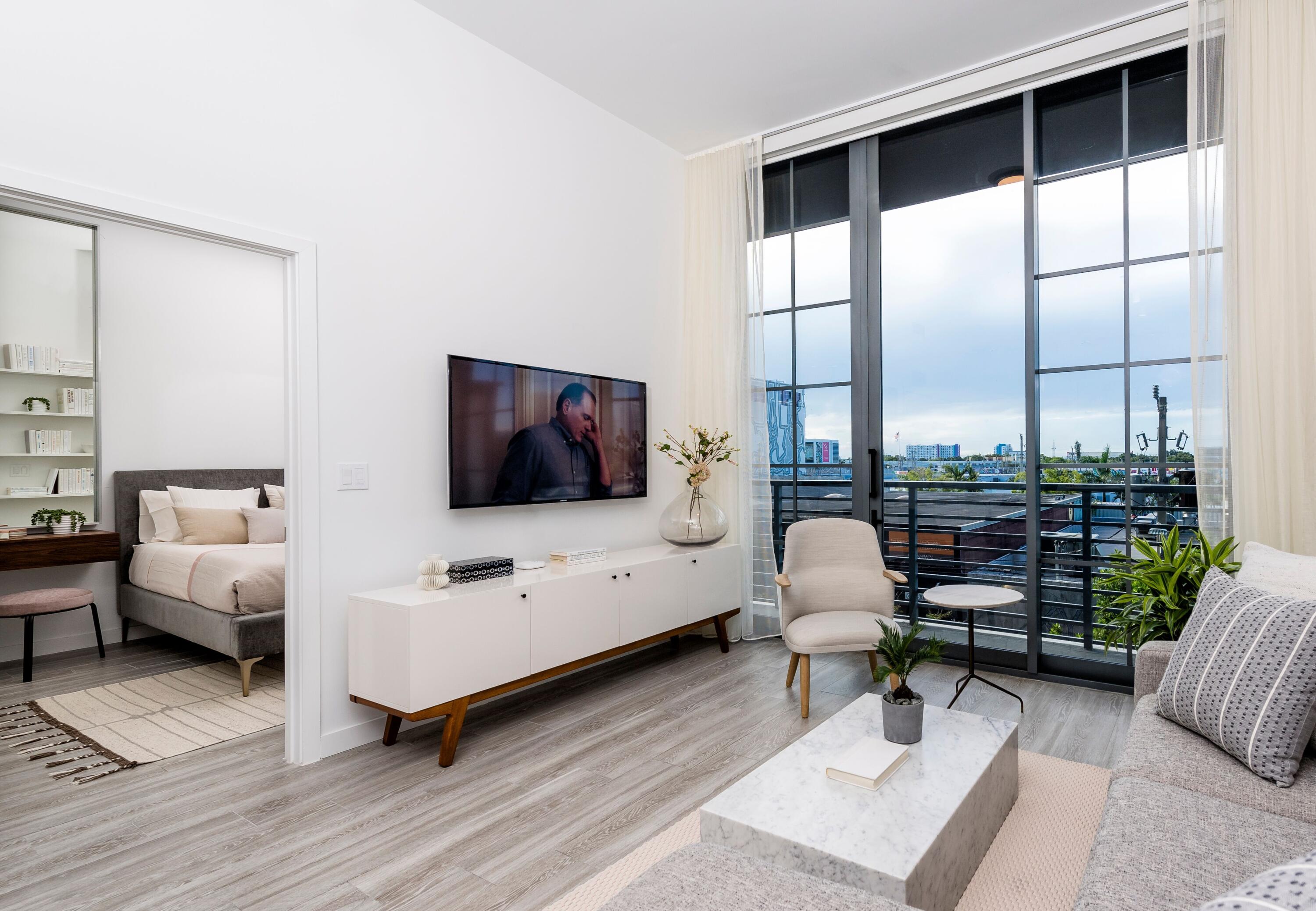 a living room with furniture tv and a floor to ceiling window