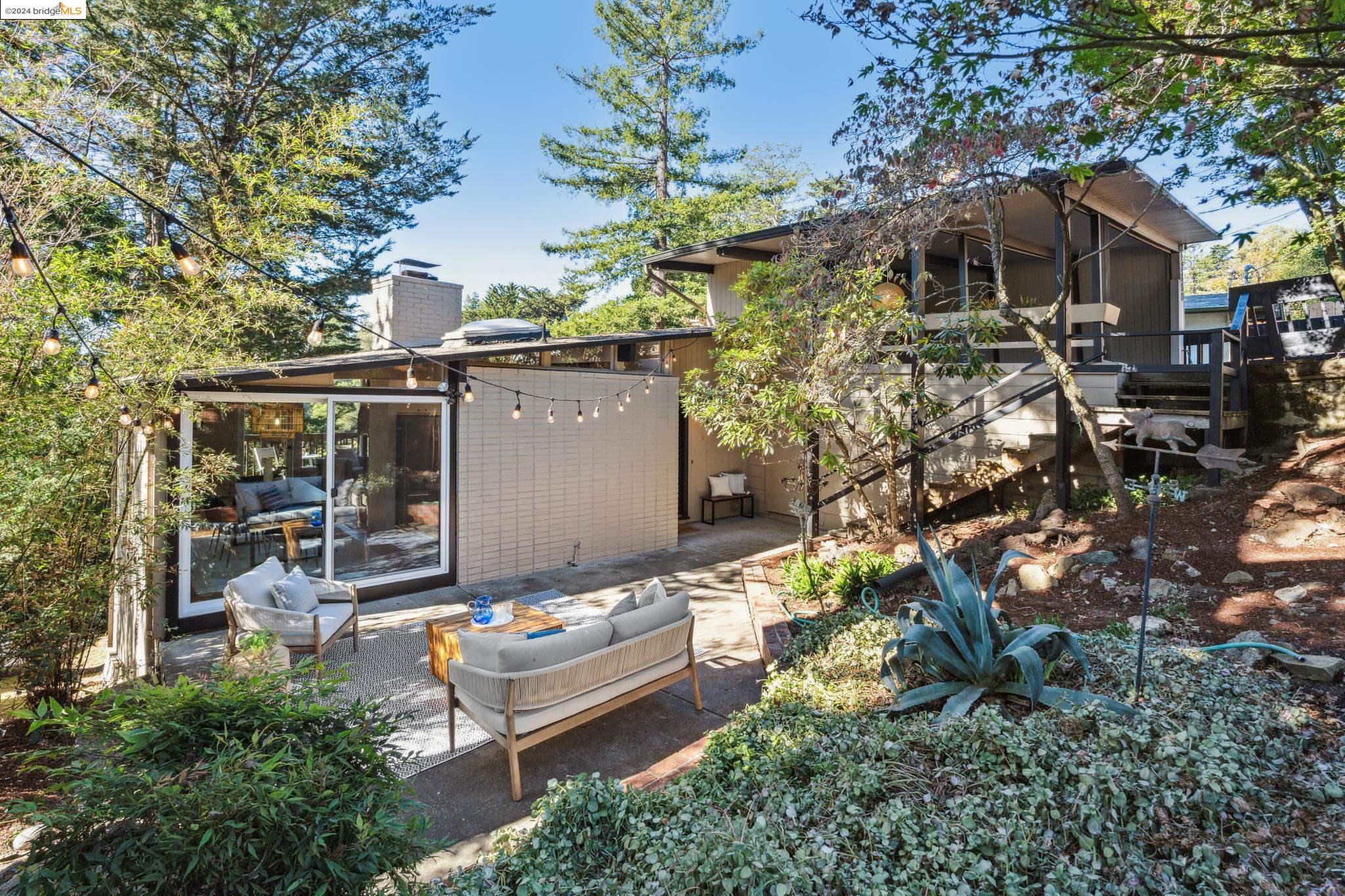 a backyard of a house with table and chairs under an umbrella