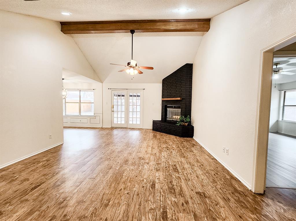 a view of an empty room with window and wooden floor