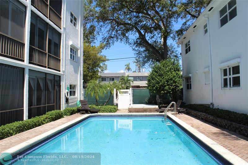 a view of swimming pool with a bench in front of house