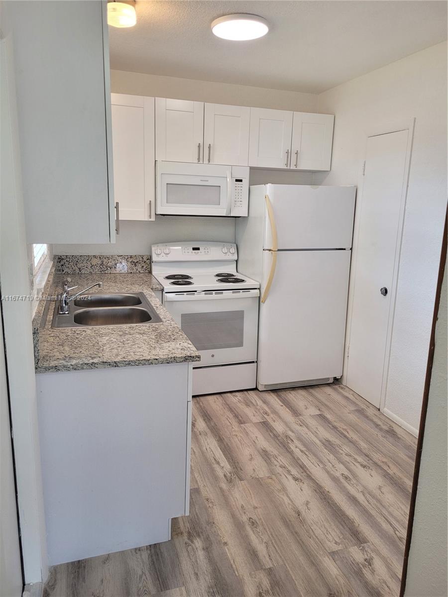 a kitchen with granite countertop white cabinets and white appliances