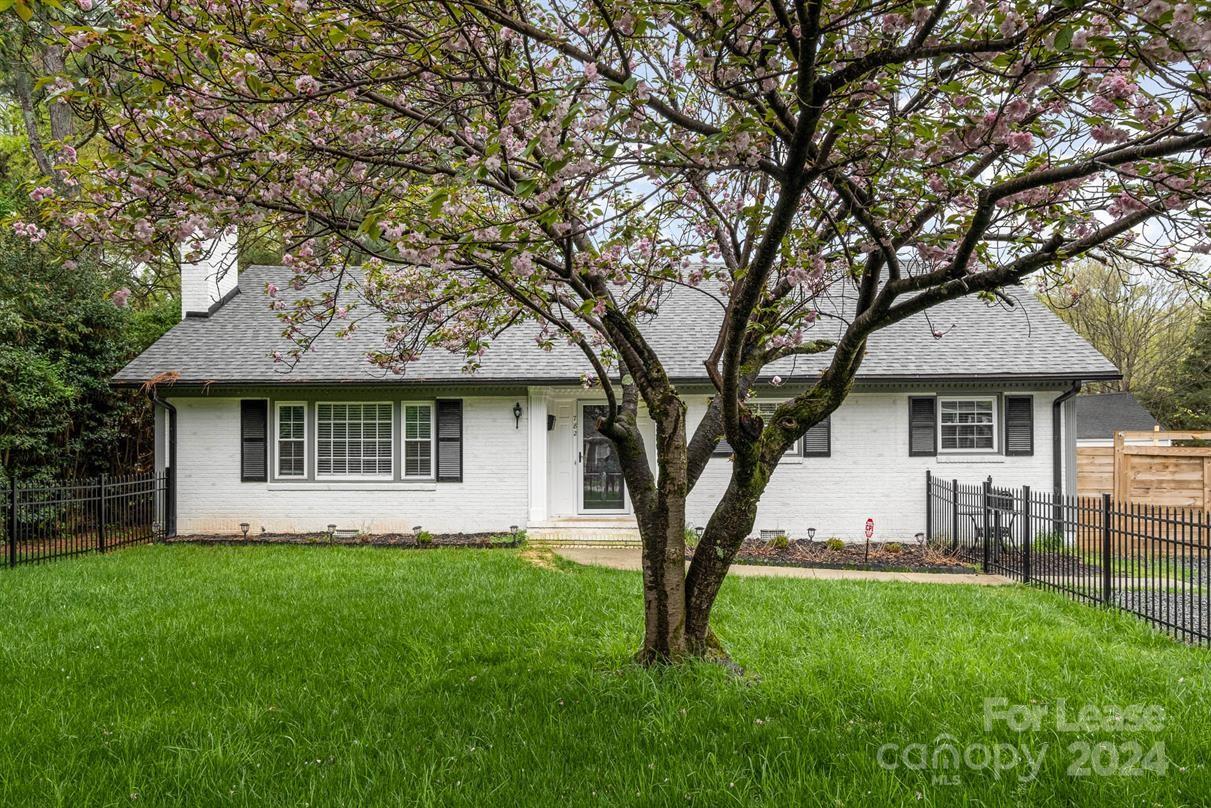 a front view of a house with a garden and trees