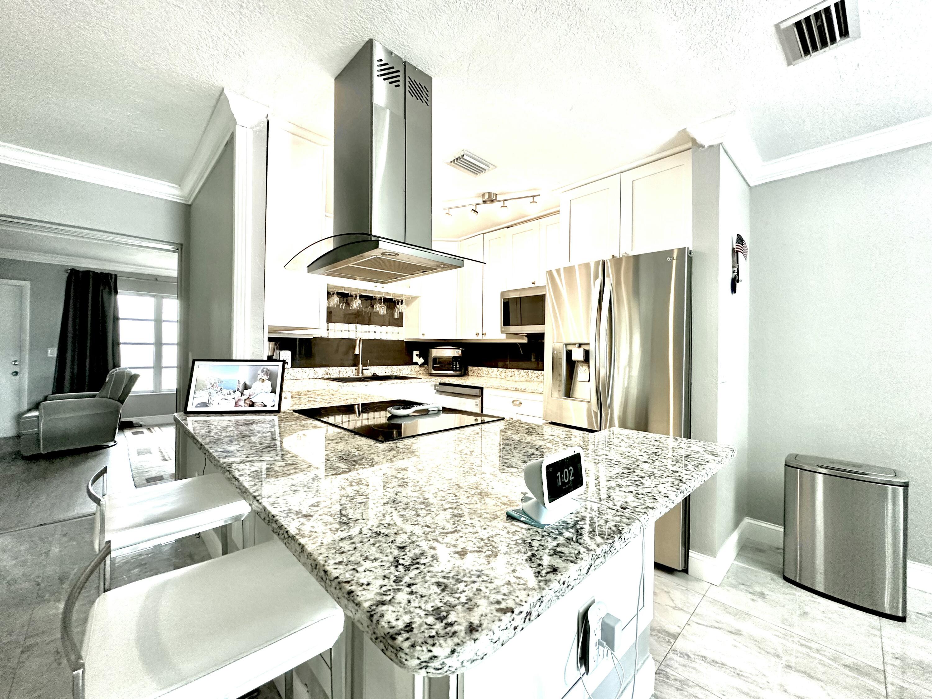 a kitchen with stainless steel appliances kitchen island granite countertop a refrigerator a stove and a sink