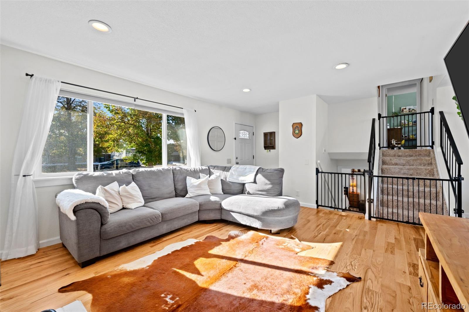 a living room with furniture large window and wooden floor