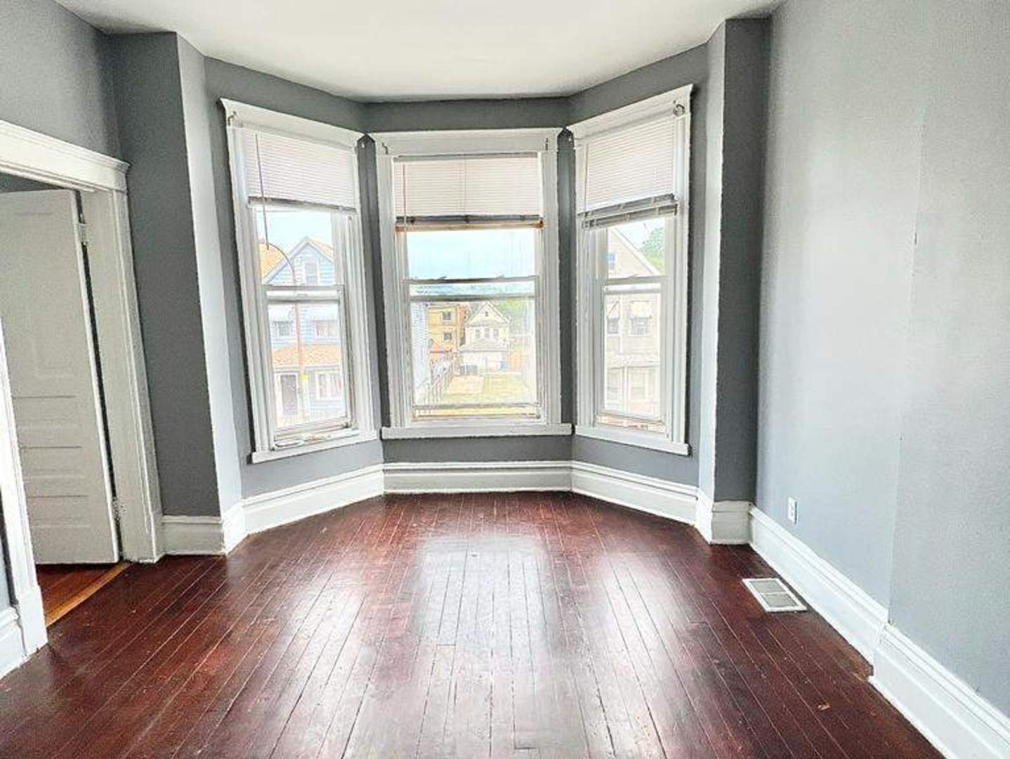 an empty room with wooden floor and windows