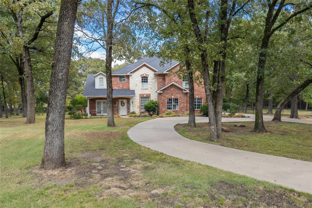 a front view of a house with a yard and large tree