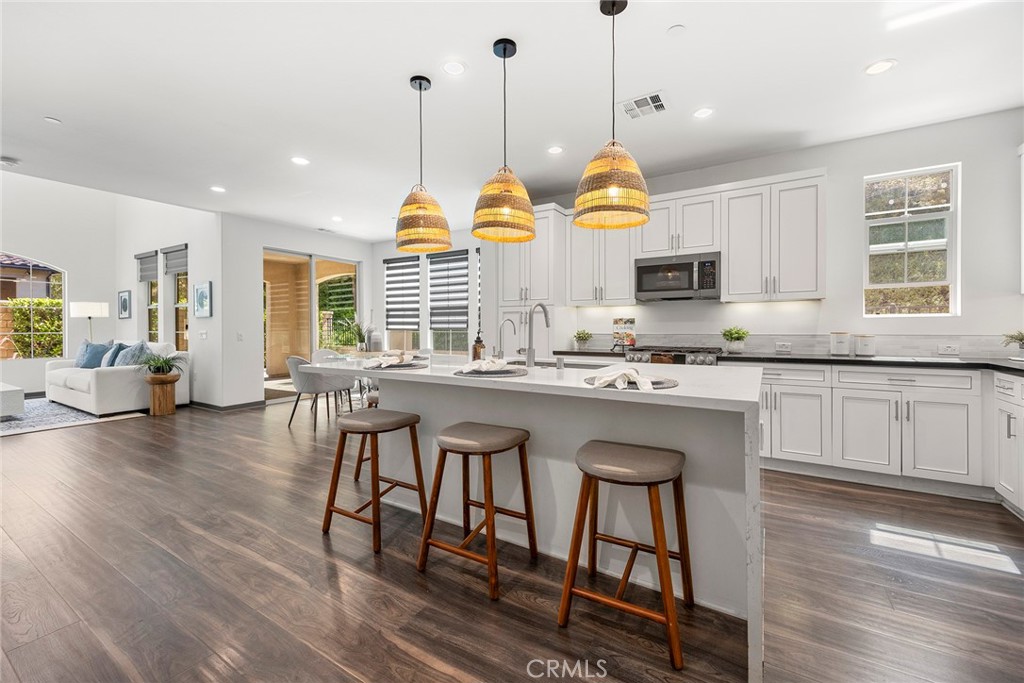 a kitchen with stainless steel appliances granite countertop wooden floors stove sink and cabinets