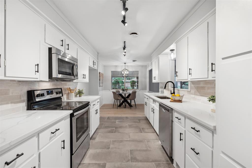 a kitchen with kitchen island granite countertop lots of counter top space sink and stainless steel appliances