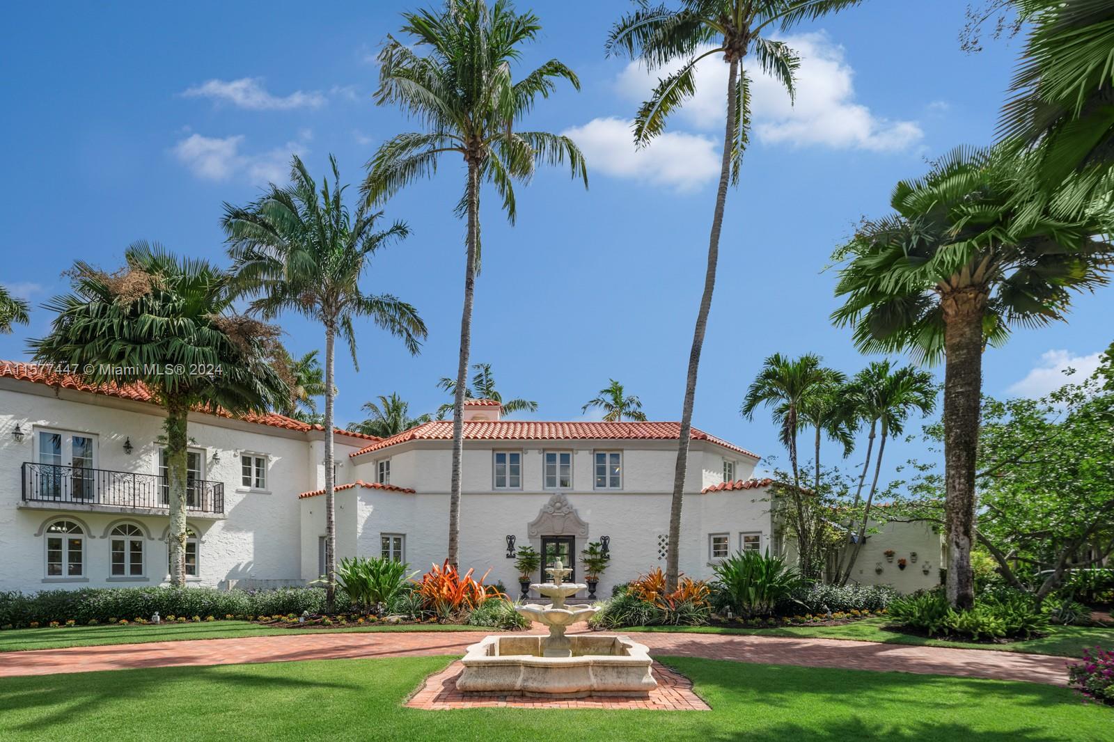 front view of house with a yard and palm trees