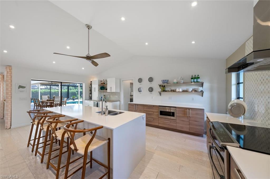 Kitchen with a kitchen island with sink, sink, lofted ceiling, decorative backsplash, and appliances with stainless steel finishes