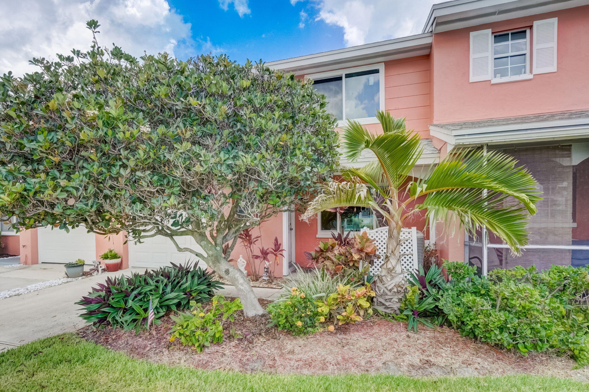 a front view of a house with plants and trees